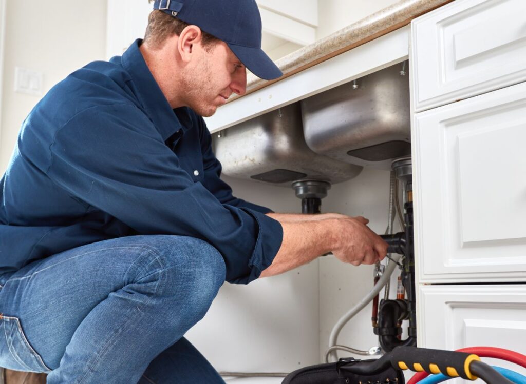 Plumber fixing under-sink plumbing in a kitchen in Reno & Sparks, Nevada
