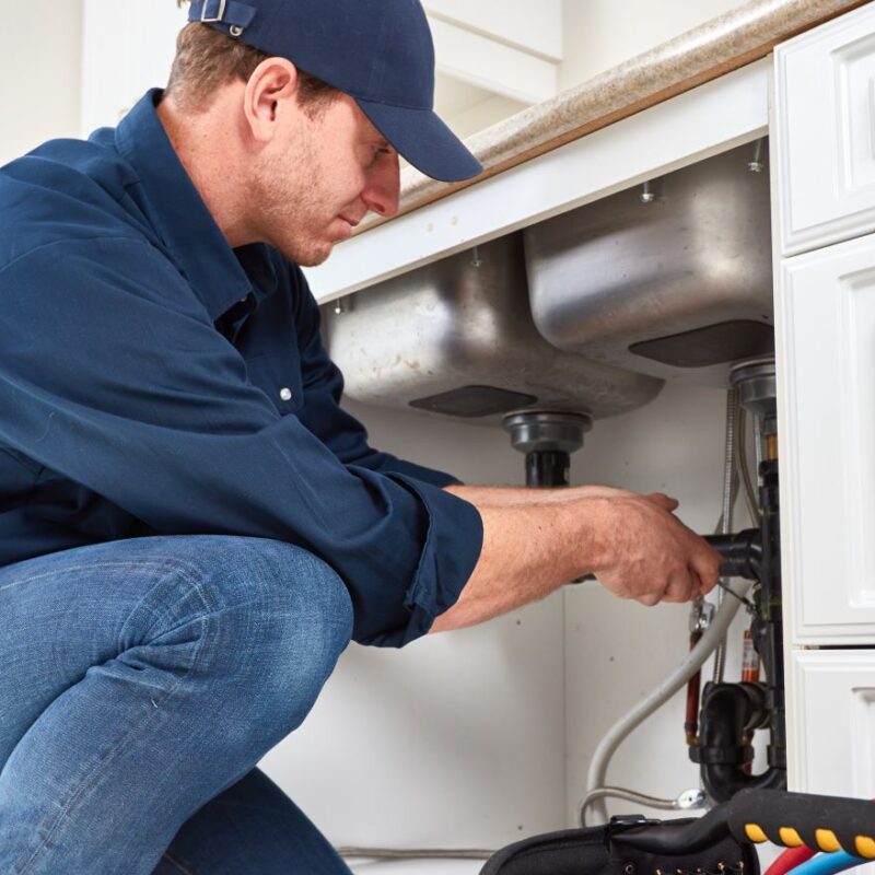 Plumber fixing under-sink plumbing in a kitchen in Reno & Sparks, Nevada