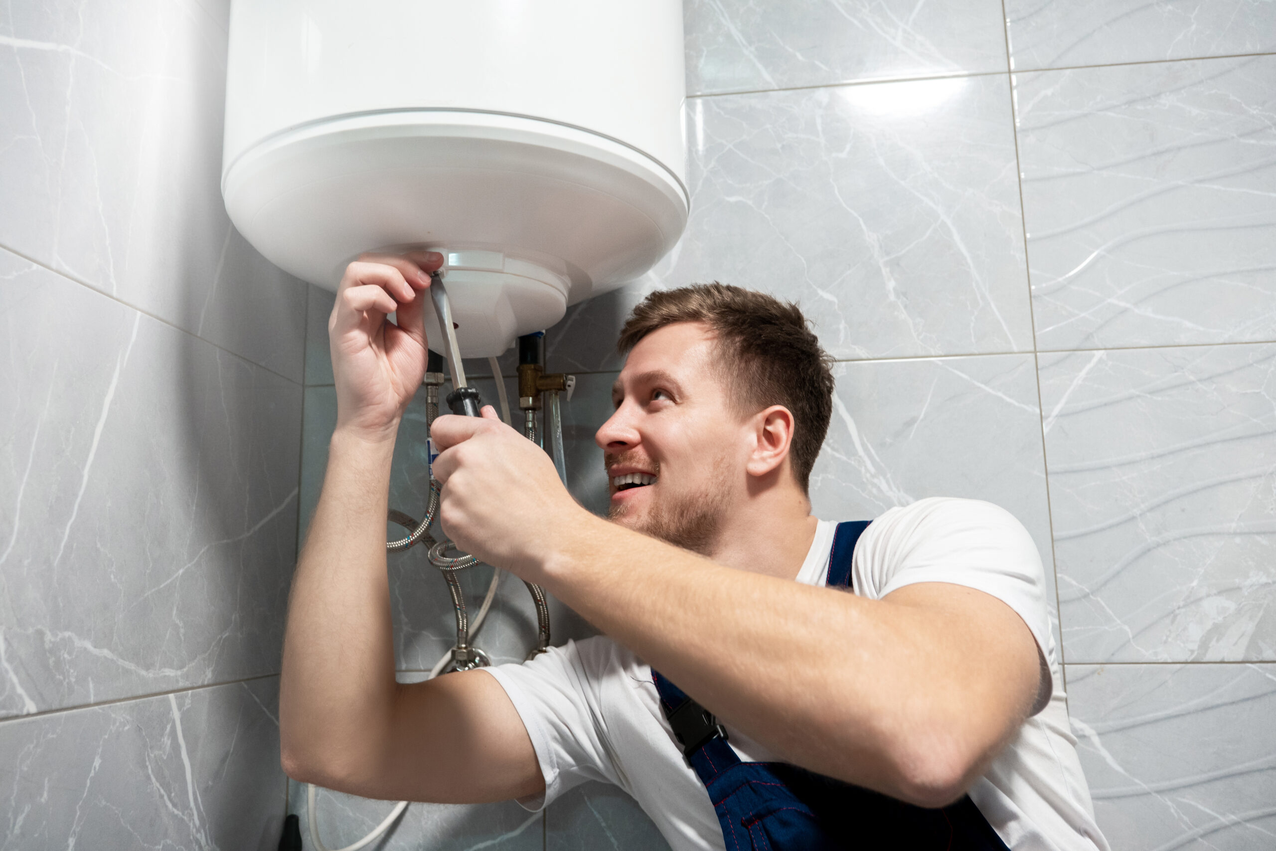 Man repairing a water heater with tools.