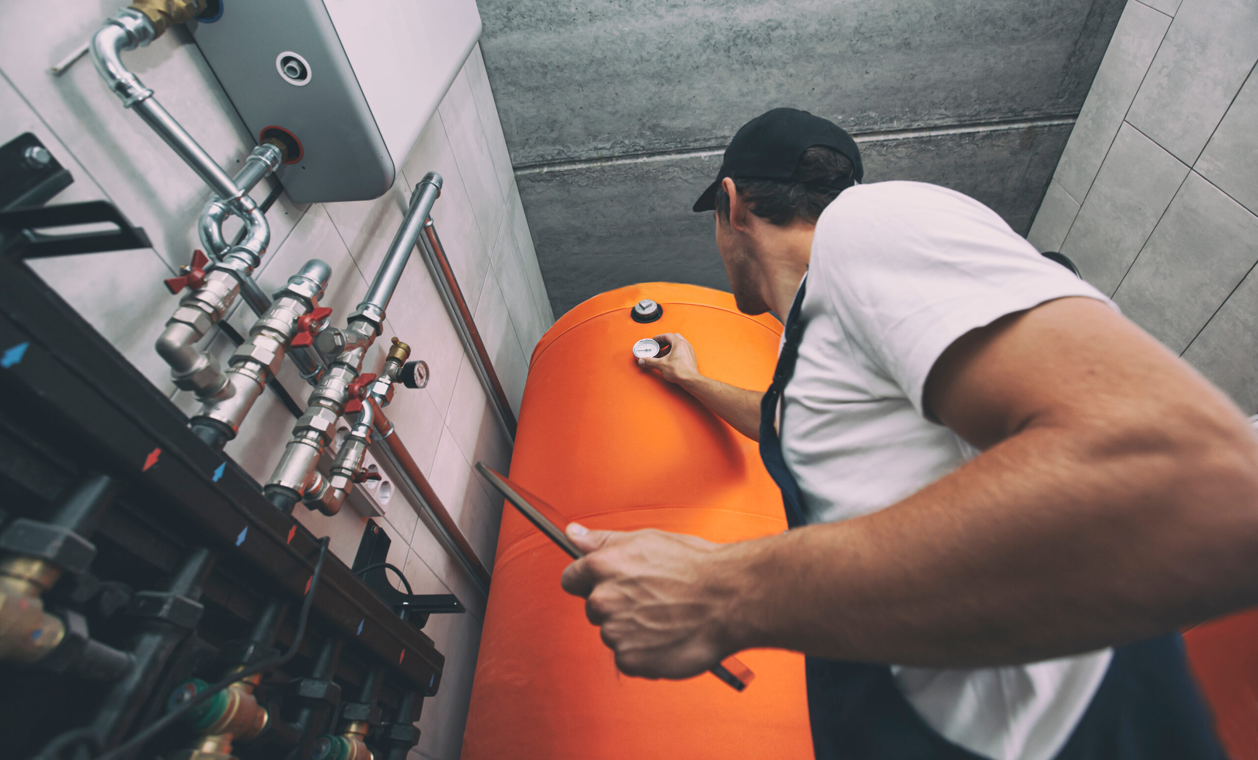 Plumber inspecting an orange water tank.