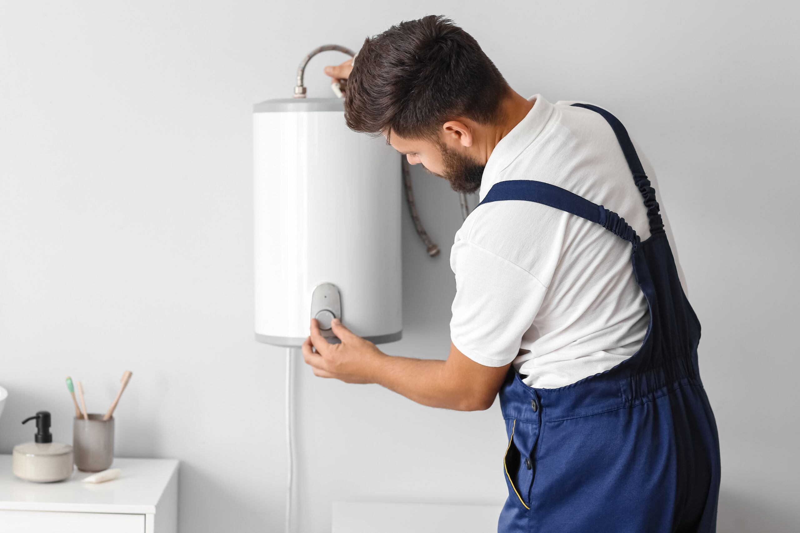 Person adjusting a water heater's temperature settings.
