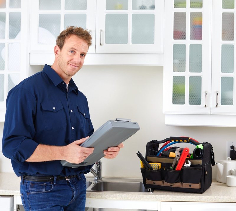Plumber with tools in a kitchen setting.