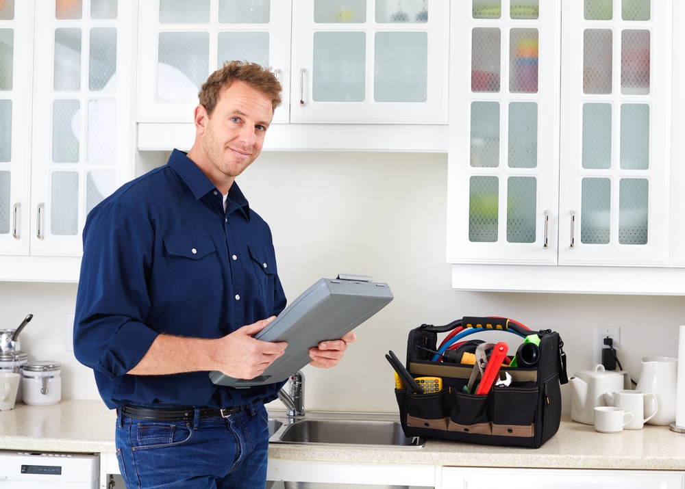 Plumber with tools in a kitchen setting.